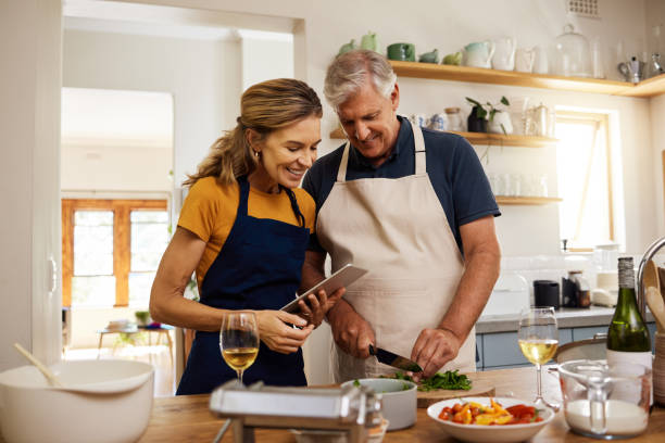food, digital tablet and senior couple cooking in kitchen in their home, checking online recipe on internet. love, family and meal with vegetables for health, wellness and nutrition while streaming - cooking senior adult healthy lifestyle couple imagens e fotografias de stock