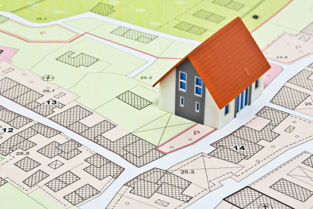 New home and free vacant land for building activity - Construction industry concept with a residential building, imaginary cadastral map, General Urban Planning and zoning regulations stock photo