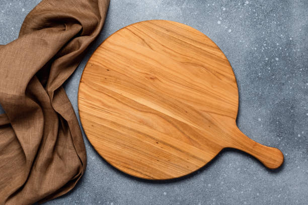 istock Round empty wooden charcuterie serving board with handle on old gray concrete background, shabby table. Top view. Food template with copy space. Flat lay design, mockup. Layout, cooking concept, frame 1454030321