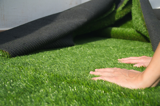 close-up of hands installing artificial grass