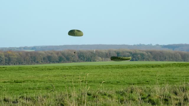 Paratroopers landing on a field during the insertion exercise in the daytime