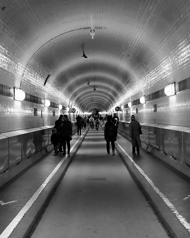 Hamburg, Germany – March 16, 2022: A grayscale view of people walking in St. Pauli Elbe Tunnel, Alter Elbtunnel in Hamburg, Germany
