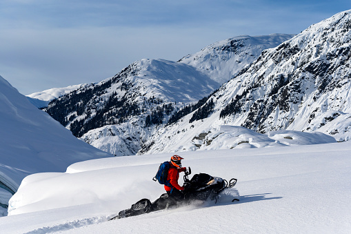 Snowmobiling fresh powder in the mountains. Extreme winter sports. Snowmobiler in British Columbia.