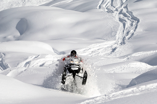 Snowmobiling fresh powder in the mountains. Extreme winter sports. Snowmobiler in British Columbia.