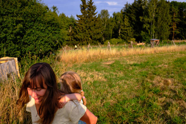 istock Mum carries her small daughter on her back during country side walk 1454040012