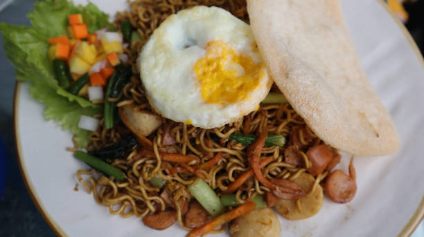 istock Asian authentic fried noodle with meat ball, veggie, shrimp crisp and egg in a plate. 1454043690