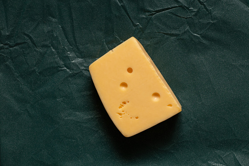 a piece of hard cheese on a colored background close-up