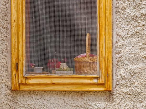Viewing through old window on village in Serbia, summer season at sunset.