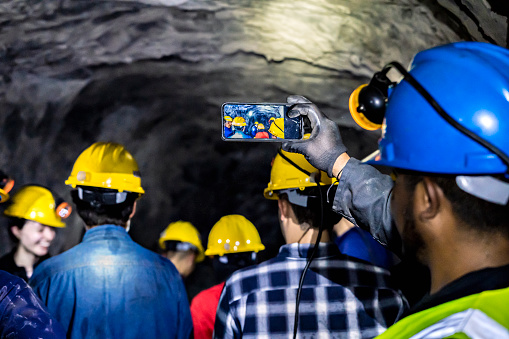 Group of miners taking photos with a cell phone in a subway mine.