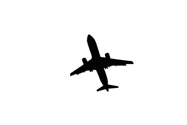 Silhouette of an unmarked passenger jet flying overhead on a plain white background. Copy space. No people.
