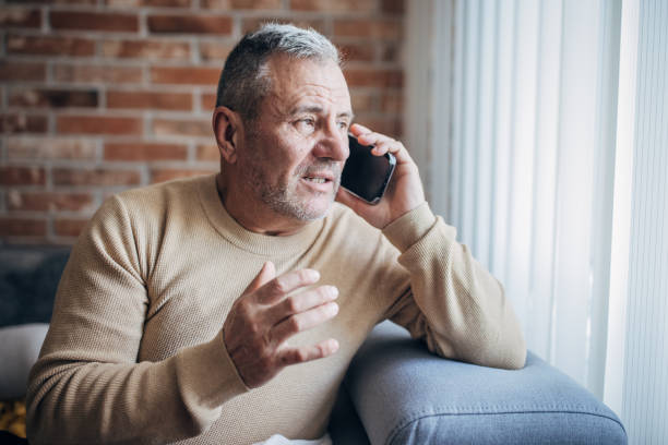 istock An elderly man sits at home and uses a mobile phone 1454054328