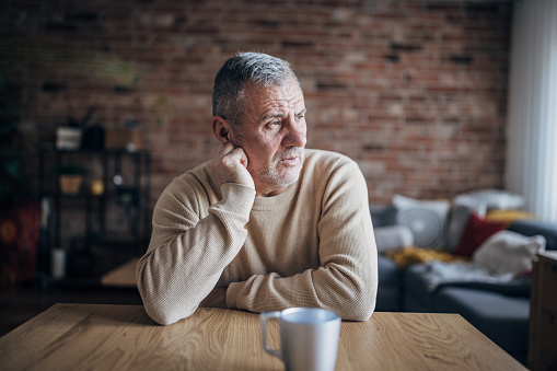 Headache, elderly man sitting alone at home