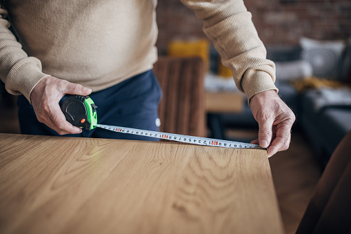 A man measures with a tape measure at home