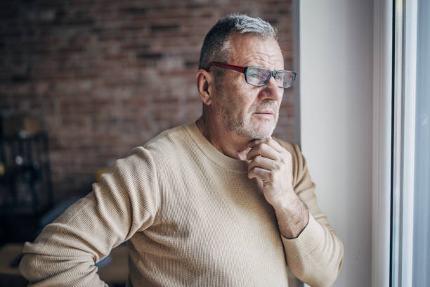 istock A senior man with glasses looks out the window 1454054731