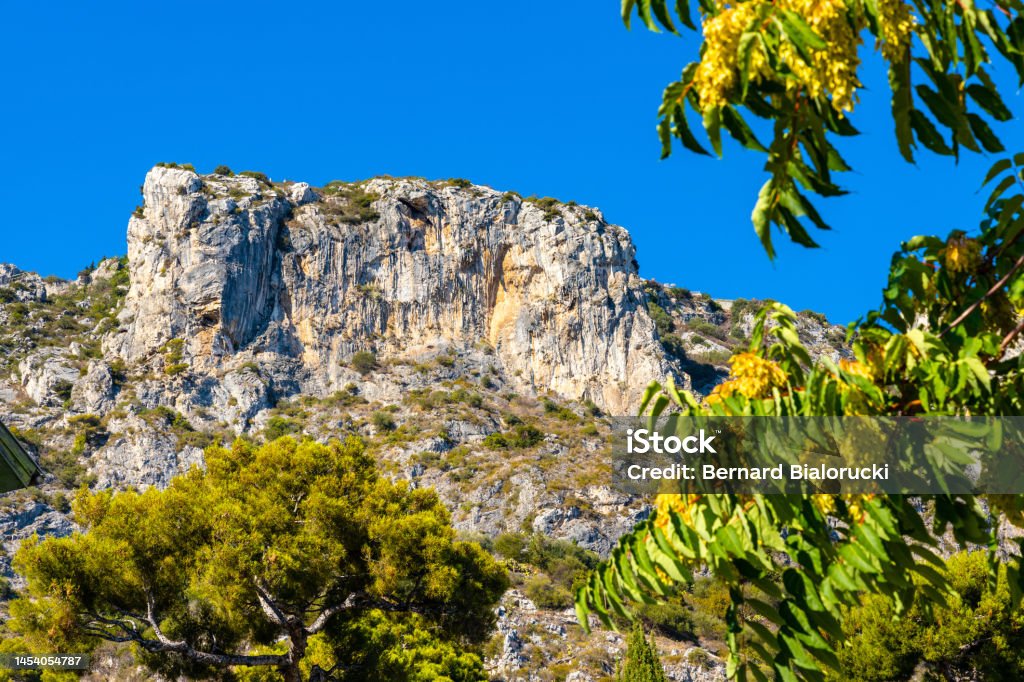 Alpes mountains and rocky cliffs over Eze sur Mer resort town on French Riviera Coast of Mediterranean Sea in France Panoramic view of Alpes mountains and rocky cliffs over Eze sur Mer resort town on French Riviera Coast of Mediterranean Sea in France Beach Stock Photo