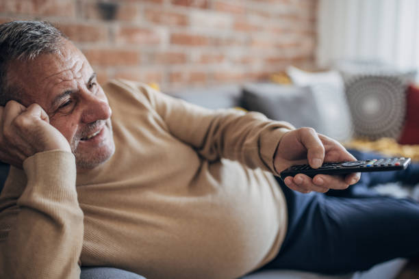 istock A fat man is lying on a sofa and holding a TV remote 1454055972