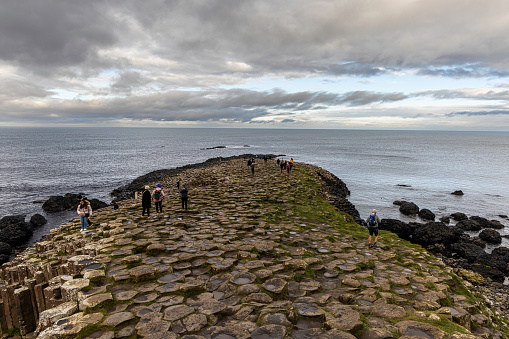 The Giants Causeway is an area of about 40,000 interlocking basalt columns, the result of an ancient volcanic fissure eruption. It is located in County Antrim on the north coast of Northern Ireland, about three miles northeast of the town of Bushmills. The tops of the columns form stepping stones that lead from the cliff foot and disappear under the sea. Most of the columns are hexagonal, although some have four, five, seven or eight sides. The tallest are about 39 ft high.