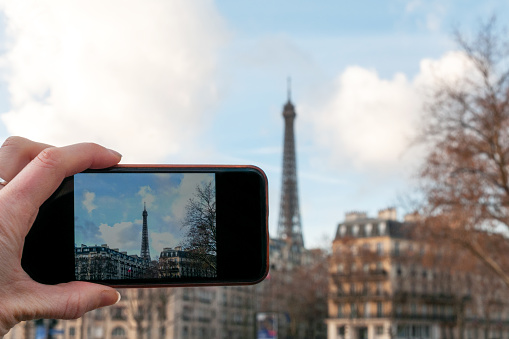 A woman taking a photo of the Eiffel Tower with a smartphone - personal perspective POV. Paris in France