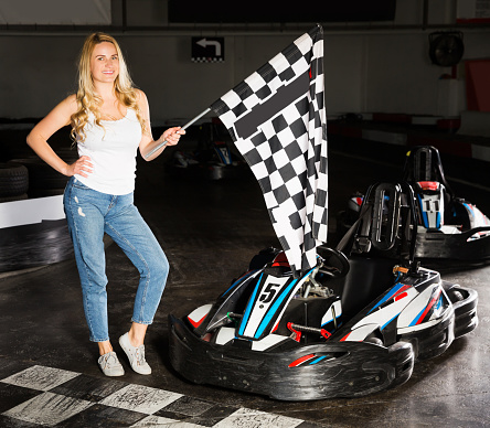 woman with checkered race flag standing near sport car for carting