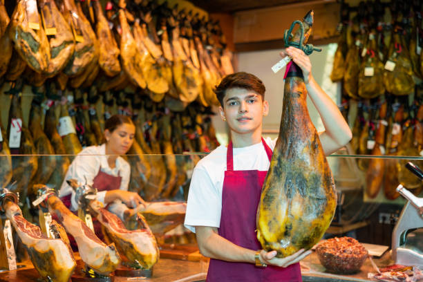istock Seller offering delectable spanish jamon in butcher shop 1454061090