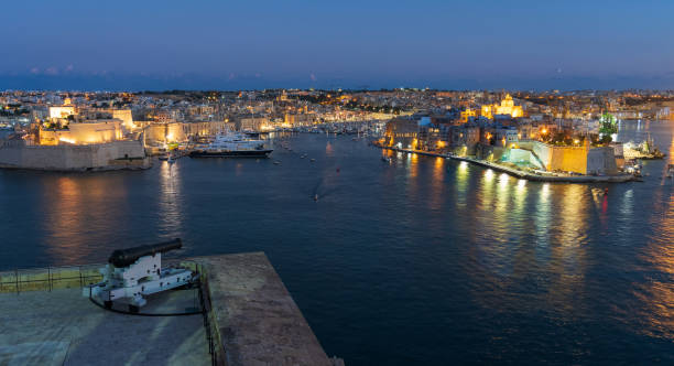Valletta, Malta waterfront at night with a cannon from the Saluting Battery in foreground stock photo