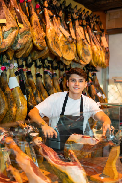 istock Cheerful young man cutting ham in jamoneria 1454061446