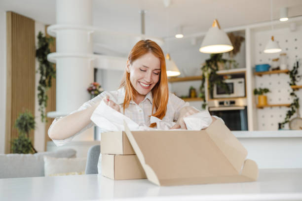 istock Young woman opens ordered items from the cardboard box 1454062683