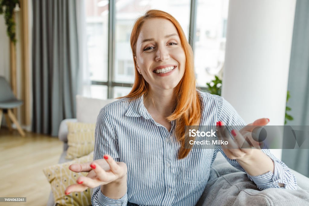 Young woman talking on a video call and looking at the camera Portrait of a young woman talking and gesturing with hands while looking at the camera Video Call Stock Photo