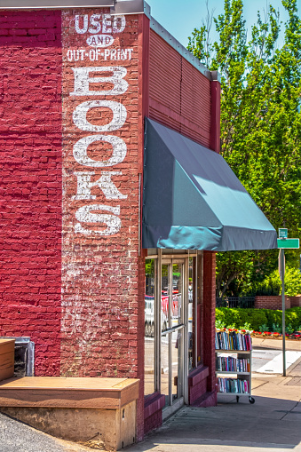 Vintage storefront used book store - Used and out-of-print books painted on brick and rolling cart of books on sidewalk