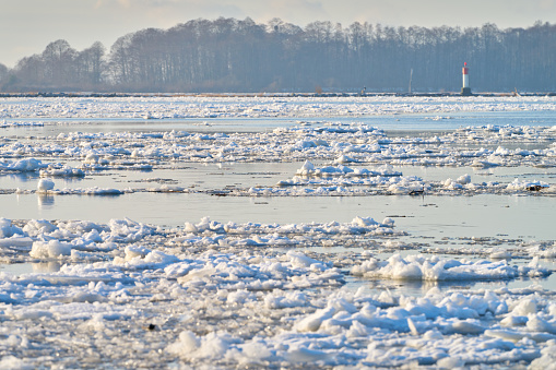 Typically dutch: ice skating on a frozen lake at Kinderdijk with view on a windmill on a cold winterday in the Netherlands