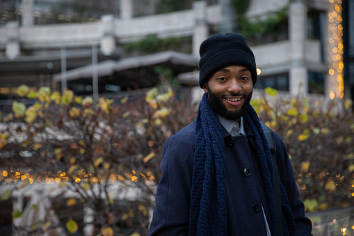 Portrait of a smiling african american man outside with blurry holiday lights in the background