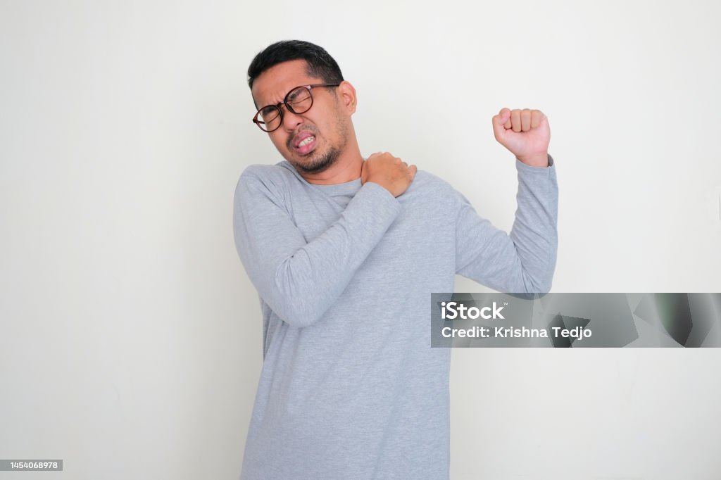 Adult Asian Man Suffering Pain In His Left Shoulder Stock Photo adult-asian-man-suffering-pain-in-his-left-shoulder-stock-photo