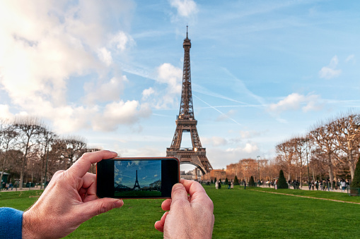 A man taking a photo of the Eiffel Tower with a smartphone - personal perspective POV. Paris in France