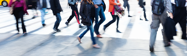picture in intentional motion blur of crowds of people crossing a city street