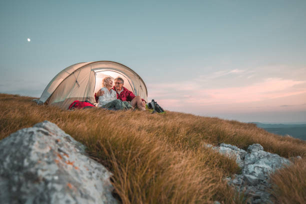 романтическая пожилая супружеская пара наслаждается уютной ночью на свежем воздухе - camping hiking tent couple стоковые фото и изображения