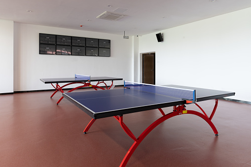 There are many tables in the empty table tennis room