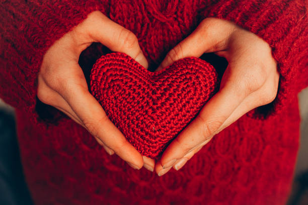 istock Female hand holding red knitted heart 1454079997