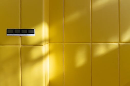The sun shines on the yellow leather anti-collision wall of the indoor sports hall