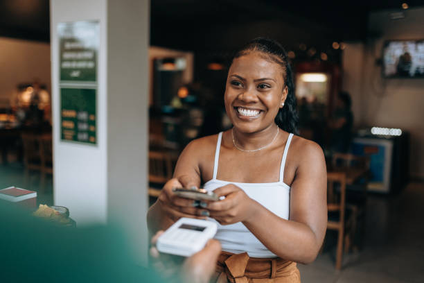 istock Woman at checkout counter using smartphone 1454083913