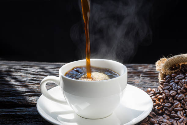 istock The steam from Pouring coffee into cup , A cup of fresh coffee on old kitchen table. with copy space. A scattering of coffee beans with a cup of coffee. Coarse fabric.hot food and healthy meal concept 1454094641