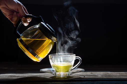 close-up view of black kettle with hot steam on black