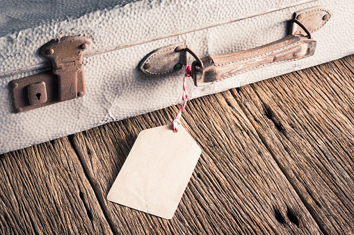 blank paper tag tie at the handle of old baggage on old wood table