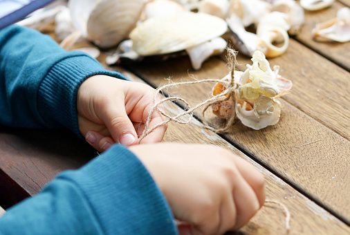 Young boy makes Christmas decorations with seashells
