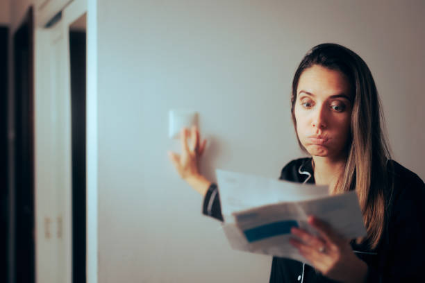 une femme vérifie sa facture d’électricité en éteignant les lumières à la maison - pushing women wall people photos et images de collection