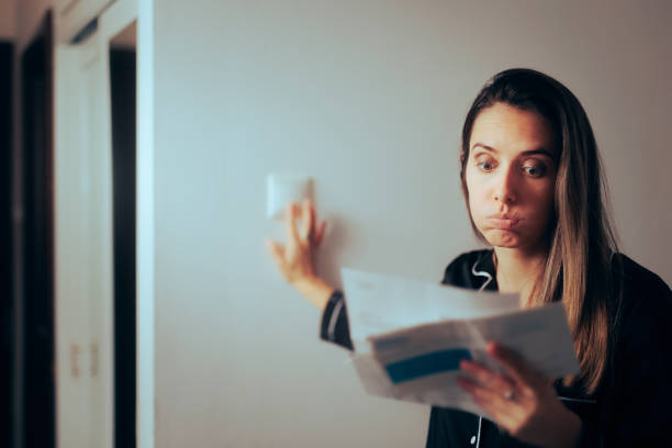 Woman Checking Electricity Bill Turning out the Lights at Home stock photo