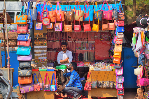 Goa, India - January 24, 2019: Street vendors selling colorful handbags in a shop.