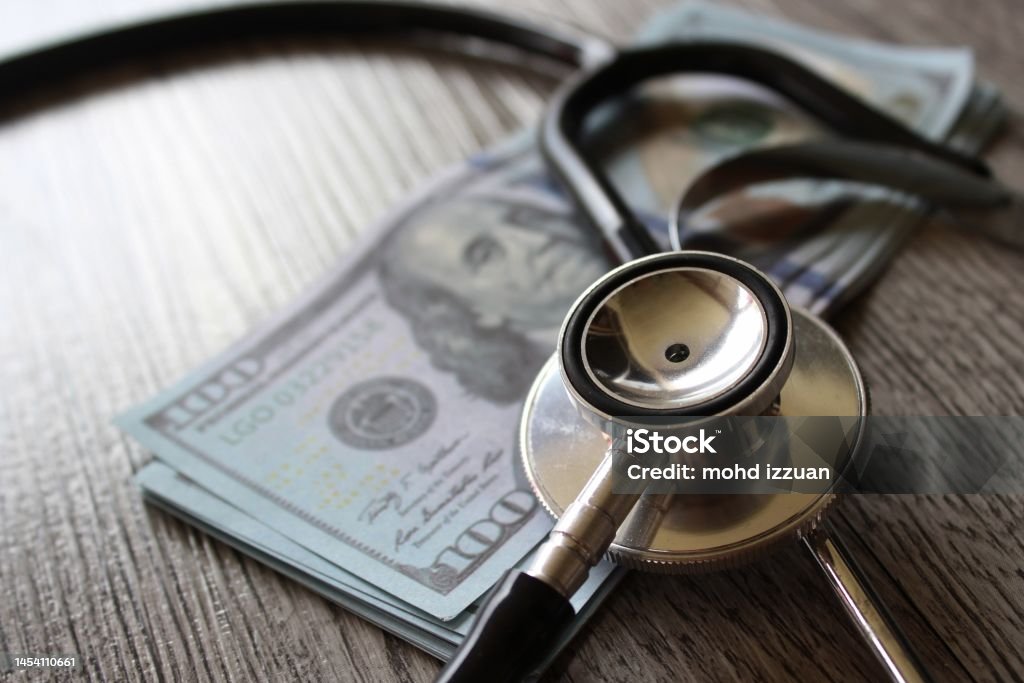 Stethoscope and money on wooden table Stethoscope and money on wooden table. Healthcare, medical treatment cost and medicine concept. Healthcare And Medicine Stock Photo