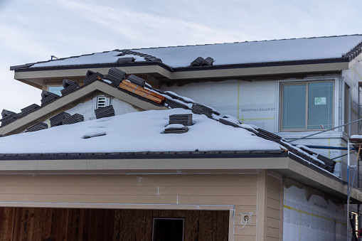 Large dangerous icicles and a roof avalanche on a house roof in winter