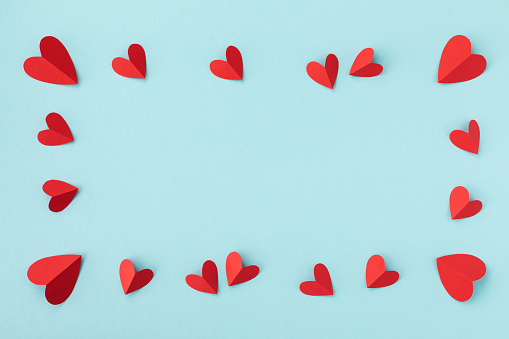 Valentine day greeting concept. Red hearts frame on blue background top view. Flat lay style.