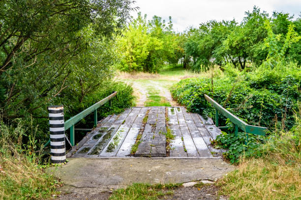 istock Beautifully standing old wooden bridge over river in colored background close up 1454119655